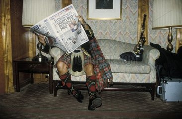 Mann in Schottenrock liest Zeitung