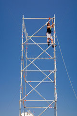 Spanien  Bauarbeiter auf einem Baugeruest vor blauem Himmel