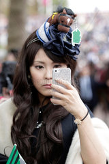 Paris  Frankreich  elegant gekleidete japanische Frau mit Hut schaut auf ihr Mobiltelefon