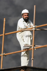 Dubai  VAE  Bauarbeiter steht auf einem Geruest vor einer schwarzen Rauchwolke