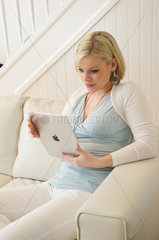 Hamburg  Deutschland  eine junge Frau auf dem Sofa mit dem IPad von Apple