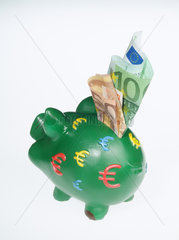 Ein gruenes Sparschwein mit Euroscheinen