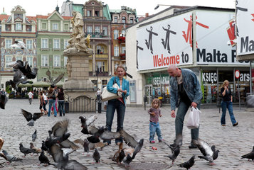 Posen  Polen  Familie fuettert Tauben auf dem Alten Markt