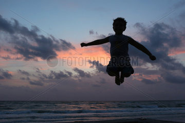 Pass A Grille  Vereinigte Staaten von Amerika  Silhouette  Junge macht einen Luftsprung bei Daemmerung am Strand