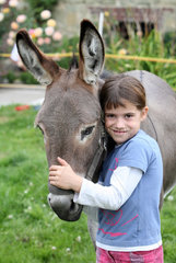Werl  Deutschland  Maedchen kuschelt mit einem Esel