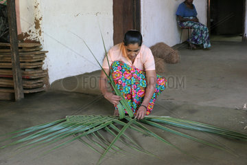 Dambulla  Sri Lanka  eine Frau flechtet eine Matte aus Blaettern der Kokospalme
