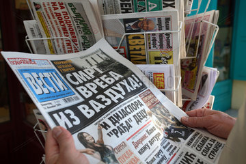 Agios Nikolaos  Mann haelt eine griechische Tageszeitung in der Hand