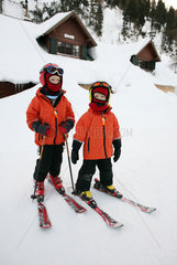 Krippenbrunn  Oesterreich  Kinder auf Skiern vor einer eingeschneiten Huette