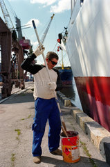 Ein Matrose streicht den Schiffsrumpf eines Frachters  Kaliningrad  Russland