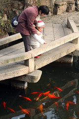 Suzhou  Frau und Kleinkind schauen sich Koikarpfen an