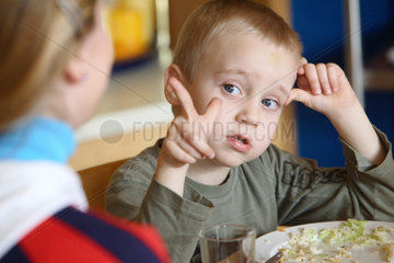 Berlin  Junge sitzt vor seinem Teller