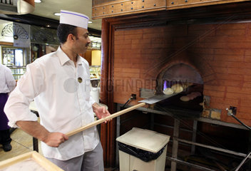 Dubai  Vereinigte Arabische Emirate  Baecker holt frische Broetchen aus einem Ofen