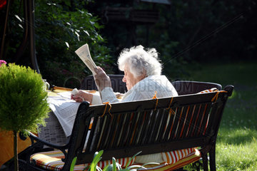 Cottbus  Deutschland  eine alte Frau liest Zeitung im Garten