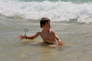 Santa Margherita di Pula  Italien  Junge im Meer sieht erschrocken Wellen auf sich zukommen