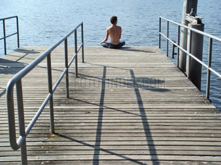 Zuerich  Schweiz  Mann sitzt an einem Bootssteg am Zuerichsee