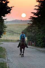 Britz  Deutschland  Reiterin bei Sonnenaufgang auf einem Distanzritt