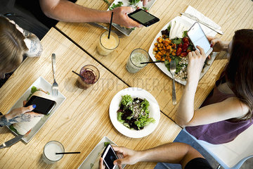 Diners using smartphones in restaurant  cropped overhead view