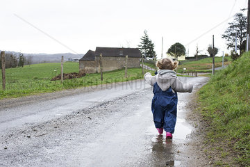 Little girl walking along wet dirt road