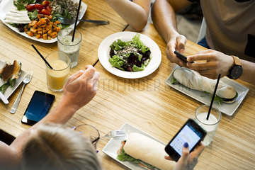 Friends using smartphones while eating in restaurant