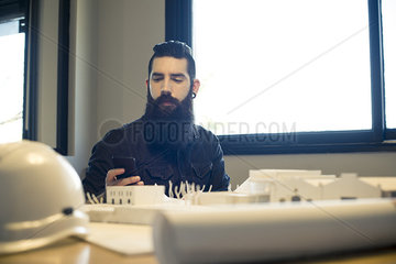 Architect looking at smartphone in office