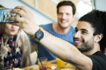 Man talking selfie with friends in restaurant