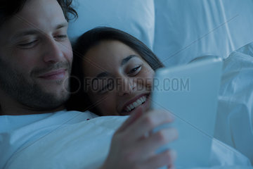 Couple using digital tablet in bed