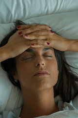 Woman lying in bed with hands on forehead