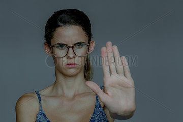 Young woman holding out palm and frowning