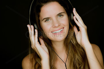 Young woman listening to headphones and smiling cheerfully  portrait