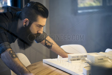 Man looking at model building in office