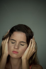 Woman holding hands over ears with eyes closed