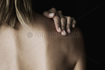 Woman rubbing her bare shoulder  cropped