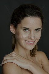 Young woman with hand on bare shoulder  smiling  portrait