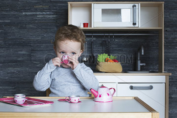 Little girl playing with toy tea set