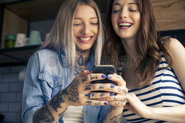 Women looking at smartphone and laughing together