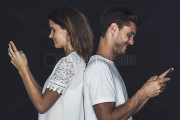 Couple back to back  both using cell phones