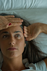Woman lying in bed with hand on forehead