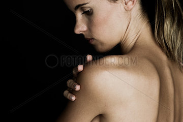 Young woman touching her bare shoulder