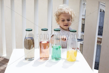 Little girl making sounds tapping bottles of water