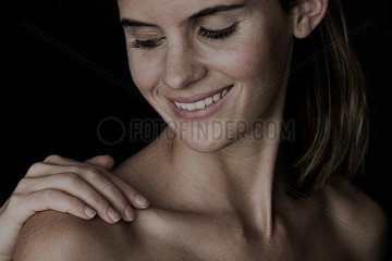 Hand touching young woman's bare shoulder