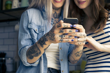 Young women looking at smartphone together  cropped