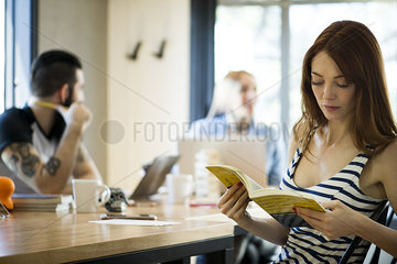 Woman reading book in shared office