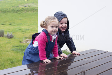 Children climbing on wet picnic table