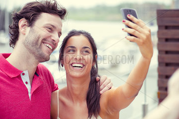 Man and woman posing for selfie taken with smart phone