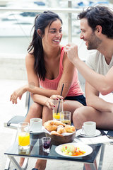 Boyfriend feeding girlfriend breakfast outdoors