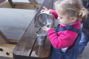 Little girl pouring water from one pail to another