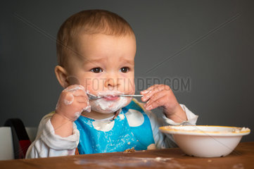 Berlin  Deutschland  ein Kleinkind mit Schnute isst Joghurt