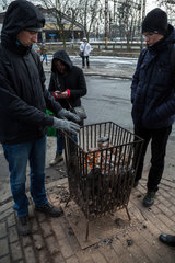 Polen  Bytom (Beuthen) - Menschen an einer Bushaltestelle waermen sich an einem Gefaess mit brennender Steinkohle
