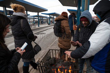 Polen  Bytom (Beuthen) - Menschen an einer Bushaltestelle waermen sich an einem Gefaess mit brennender Steinkohle