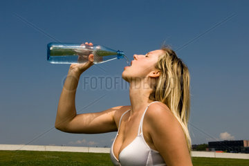 Junge Frau tringt Wasser aus einer Flasche  Berlin
